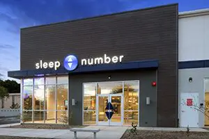 A woman standing outside of a sleep number store.